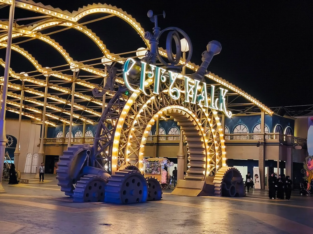Illuminated Jeddah City Walk entrance at night.