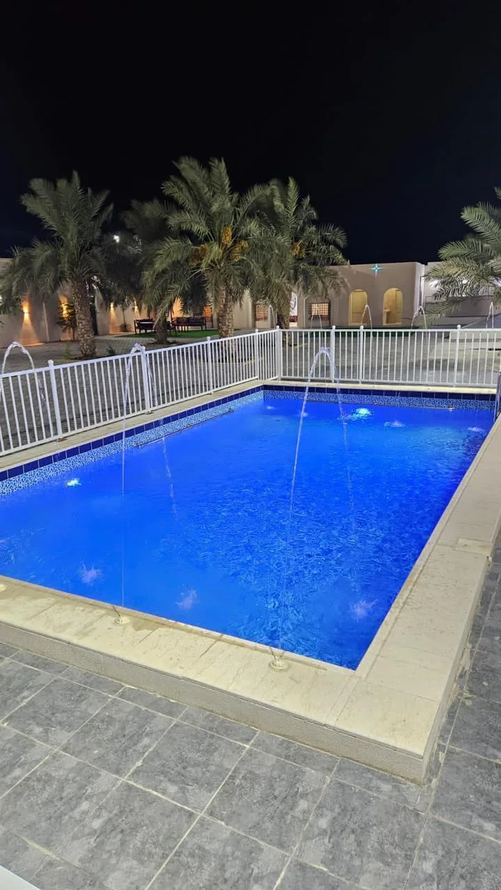 The fenced pool at the private Istiraha at night.