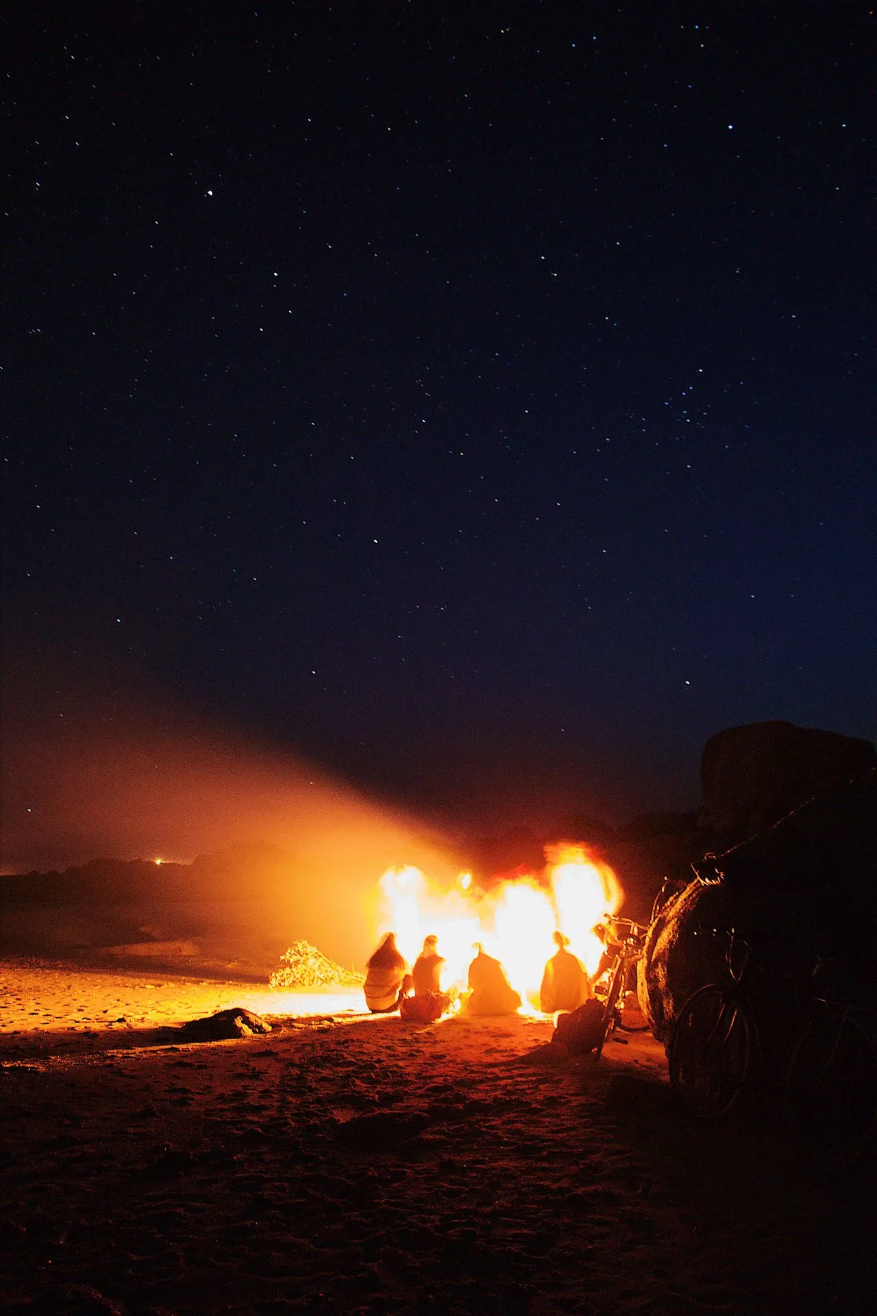 A group around a desert bonfire beneath the night sky.