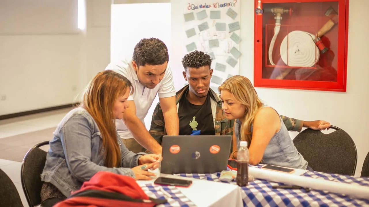 People collaborating around a laptop in a class.